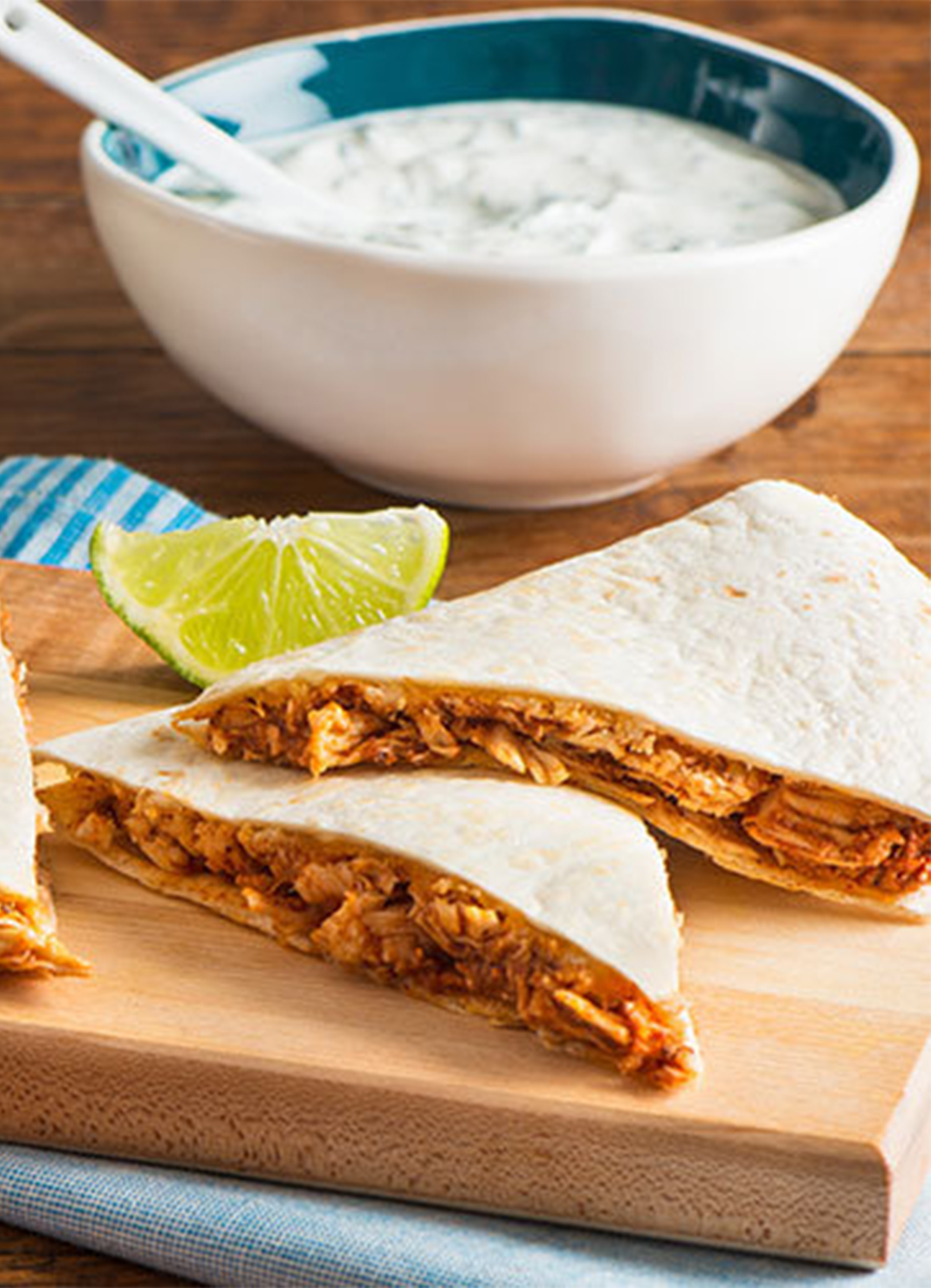 Chicken quesadillas served on a platter with fresh lime wedges and yogurt-mint dipping sauce