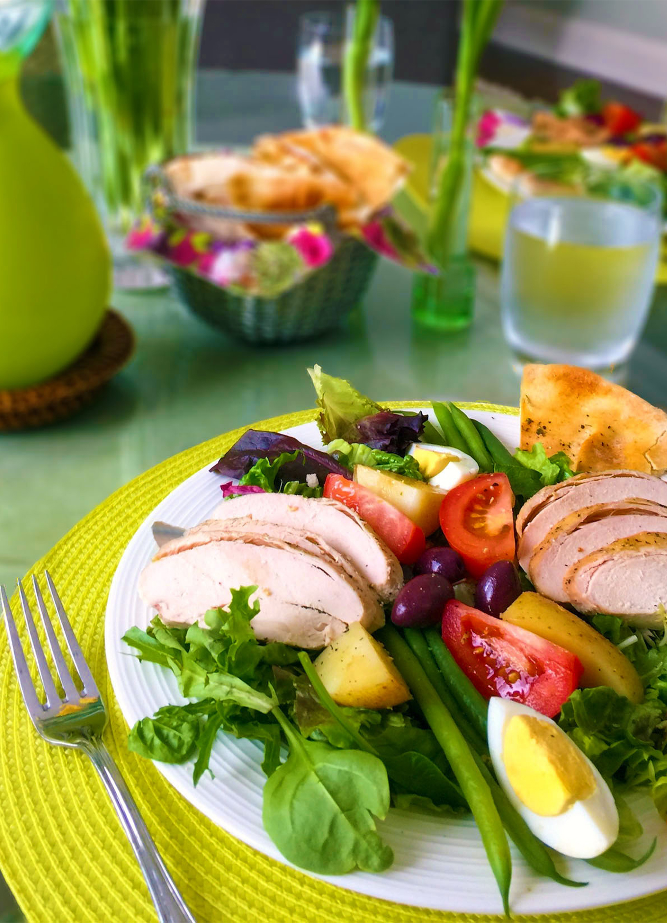 Une salade niçoise avec des poitrines de poulet Zabiha Halal et des légumes frais, reposant sur une table colorée