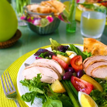 A Nicoise salad made with Zabiha Halal Chicken Breasts and fresh vegetables, on a colourful table.