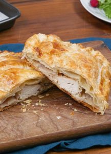 Flaky pastry filled with Chicken, herbs, cranberries, and cream cheese on a festive table setting.