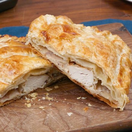 Flaky pastry filled with Chicken, herbs, cranberries, and cream cheese on a festive table setting.