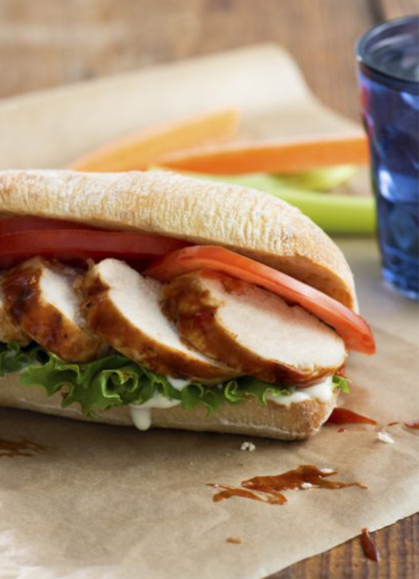 A fresh bun with generous slices of Grilled Buffalo Chicken with lettuce, tomato and sauce.