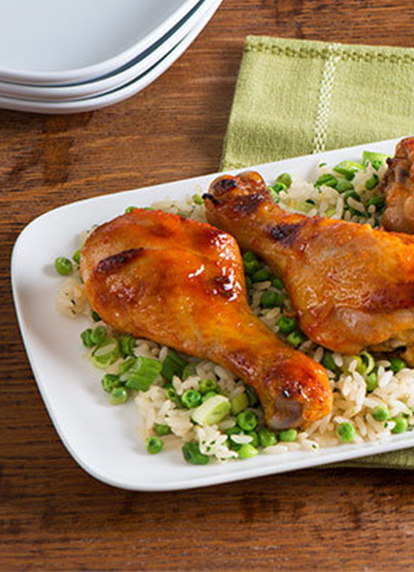 A tray of roast drumsticks with a honey and Sriracha glaze served on a bed of rice and peas.