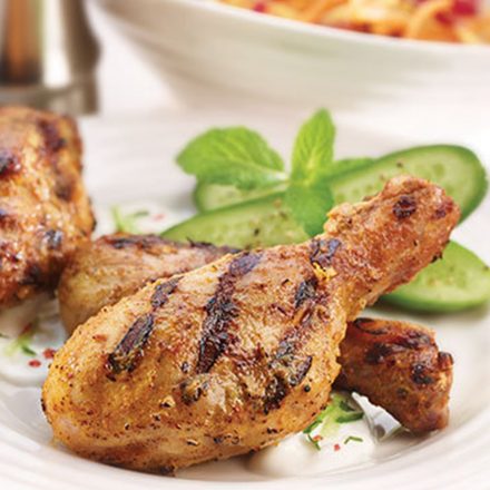 Grilled Indian Spiced BBQ Drumsticks plated with cucumber and mint, with yogurt dipping sauce