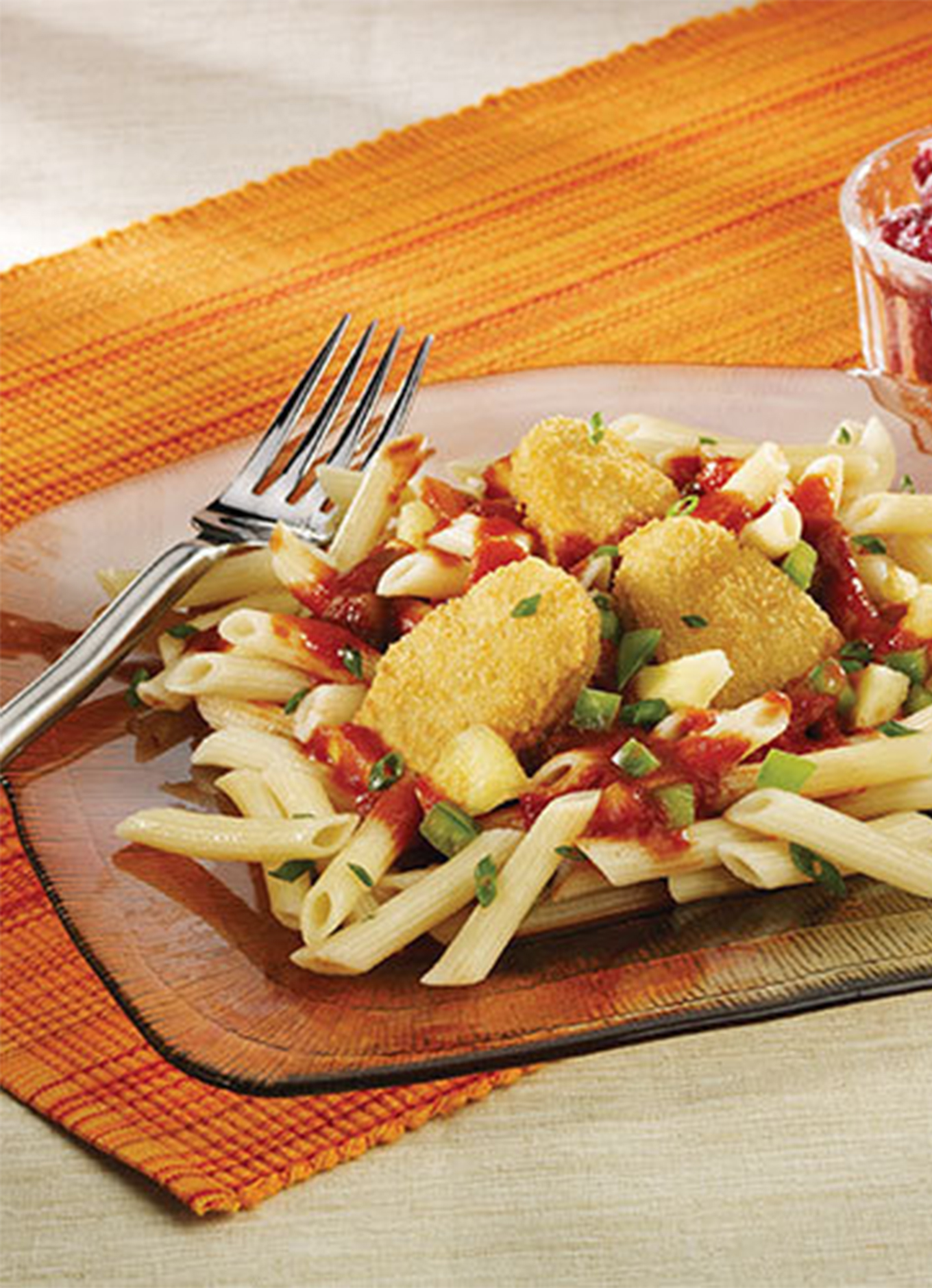 Pineapple Chicken Nuggets on a tropical bed of pasta with a side of fresh raspberries.