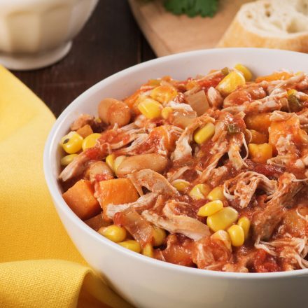A steaming bowl of Slow Cooker Chicken & White Bean Chili with pulled chicken, corn, and white beans.