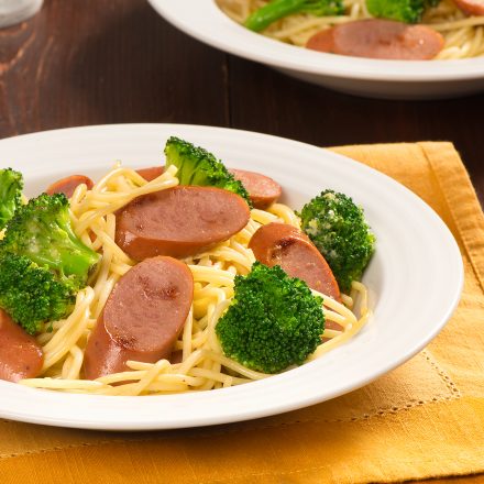 A table set with two places of Smoked Chicken Sausages & Broccoli Spaghetti Carbonara.