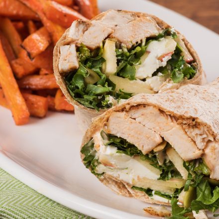 A cross section of a Spiced Chicken Wrap with a side of roasted carrot fries