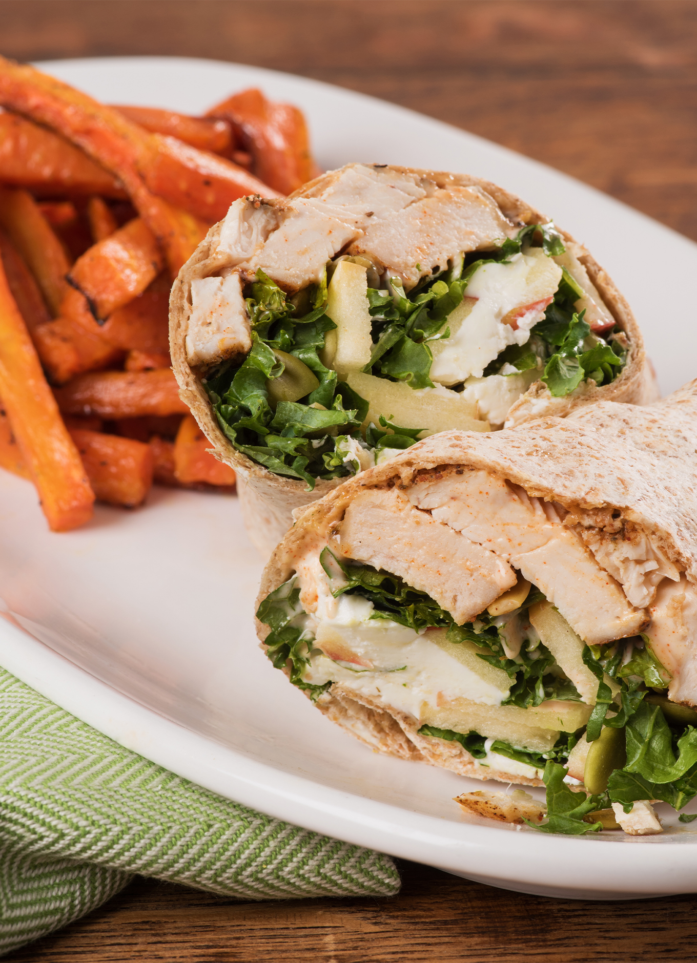 A cross section of a Spiced Chicken Wrap with a side of roasted carrot fries