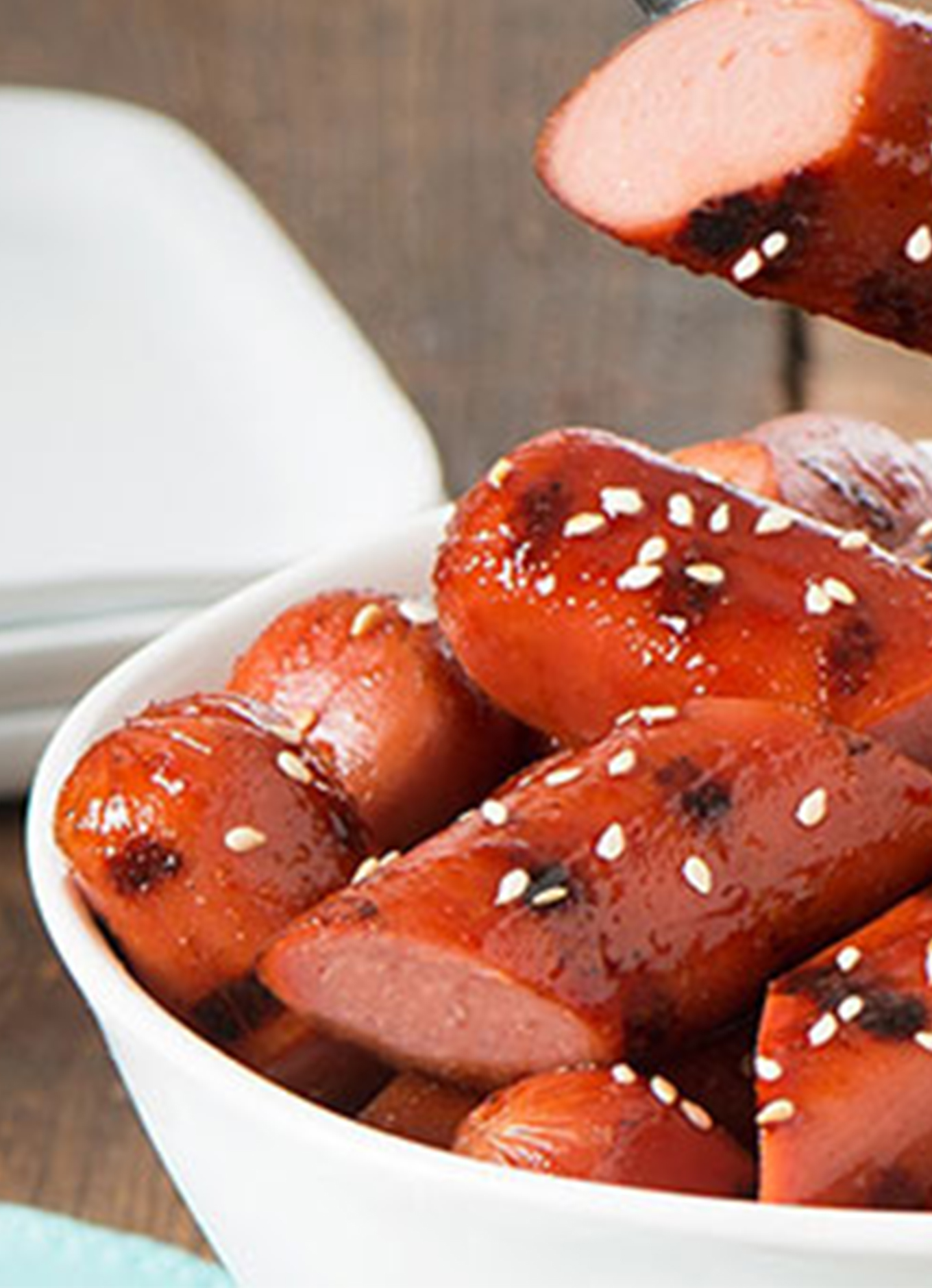 A bowl of grilled Sweet & Spicy Hot Dog bites topped with sesame seeds